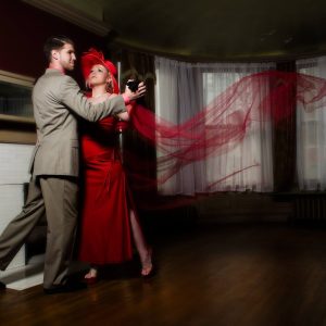 A woman in red dances with a man