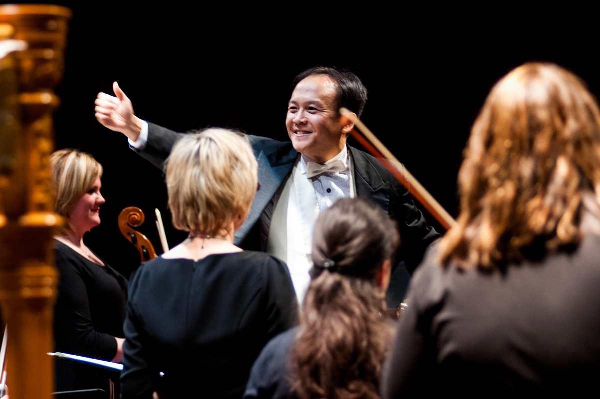 Holiday Events - A man in a black tuxedo gestures to four orchestra players