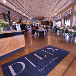 View of the hostess stand with a large rug that reads DLX at the entrance to Cafe on Main
